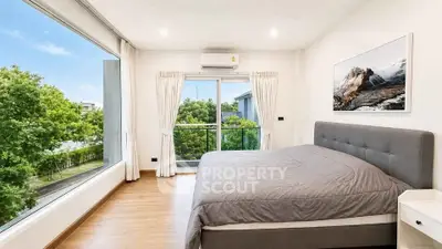 Spacious bedroom with large windows offering lush green views, modern decor, and ample natural light.