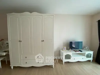Spacious bedroom with elegant white wardrobe and TV stand, perfect for modern living.