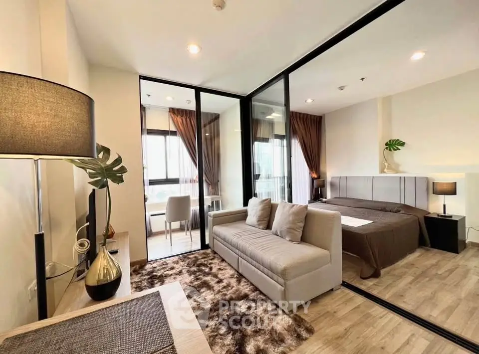 Modern studio apartment with glass partition, cozy living area, and stylish bedroom.