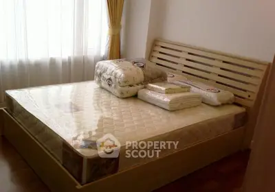 Cozy bedroom with natural light and wooden bed frame, perfect for relaxation.