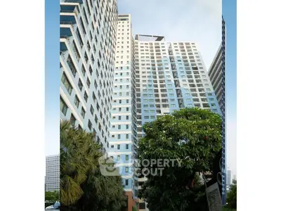 Modern high-rise residential building with lush greenery and urban skyline view.