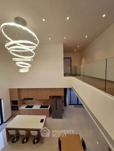 Luxurious modern kitchen with high ceilings and elegant lighting in a spacious open-plan design.