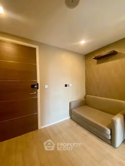 Cozy small living room with modern sofa and wooden door, perfect for compact spaces.