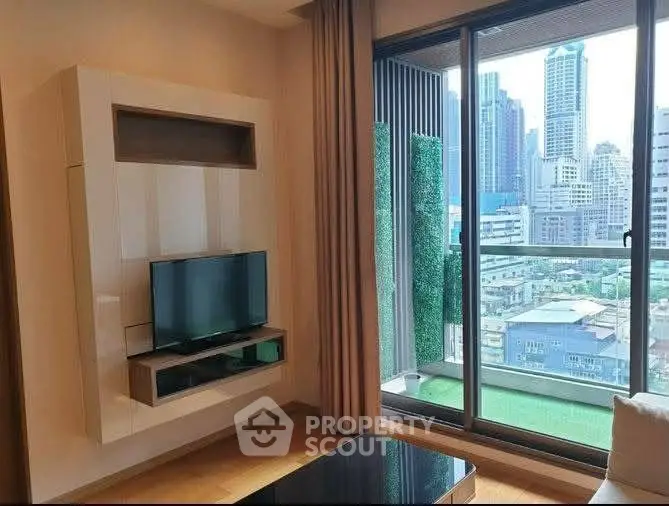Modern living room with city view, featuring sleek TV unit and large windows opening to a balcony.