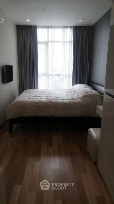 Cozy bedroom with large window and modern decor in a stylish apartment.