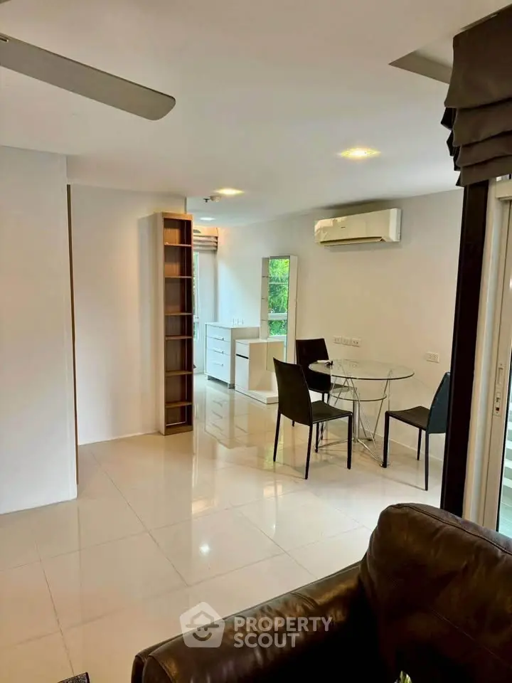 Modern living room with dining area and air conditioning, featuring sleek furniture and natural light.