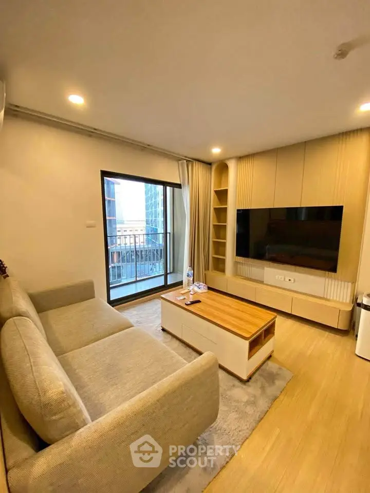 Modern living room with cozy sofa, large TV, and balcony view in stylish apartment.
