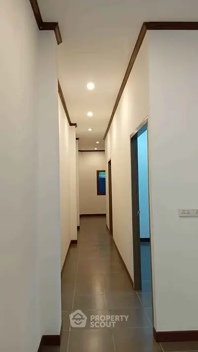 Modern hallway with recessed lighting and tiled flooring in a contemporary home.