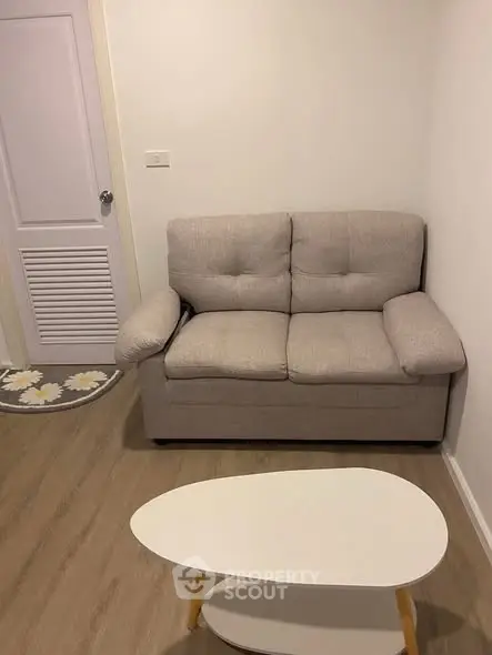 Cozy living room with beige sofa and modern coffee table in a compact space.