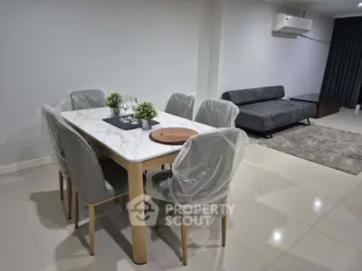 Modern dining area with marble table and cozy living space, featuring sleek furniture and elegant decor.