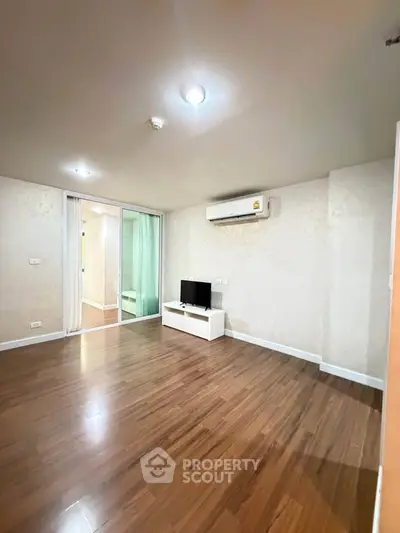 Spacious living room with wooden flooring and modern air conditioning unit.