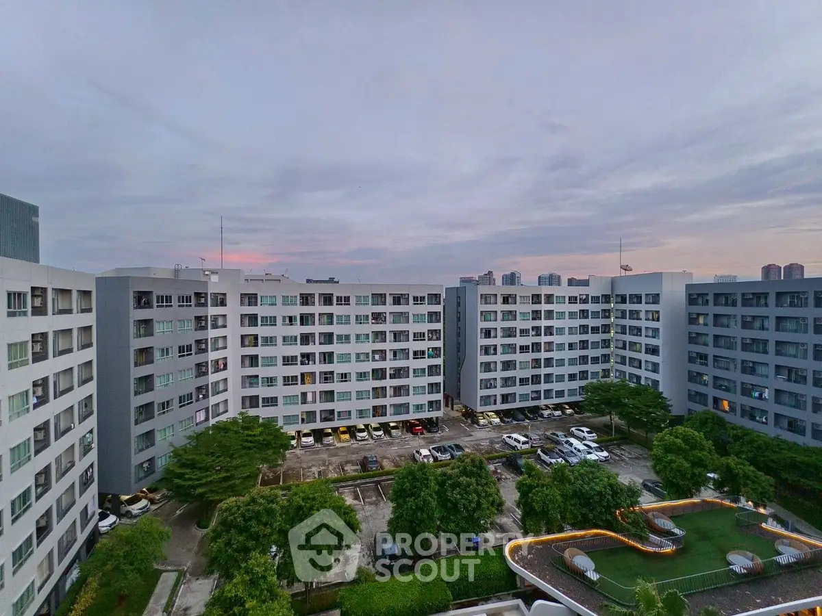 Stunning aerial view of modern apartment complex with lush greenery and spacious parking area.