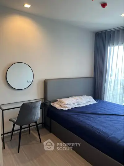 Modern bedroom with stylish decor and natural light, featuring a cozy bed and sleek desk setup.