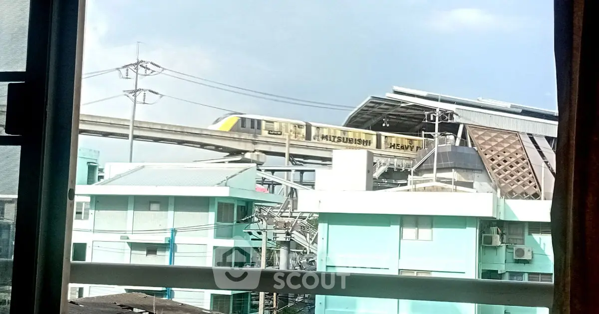 Urban view from window showcasing train station and cityscape, ideal for city living enthusiasts.