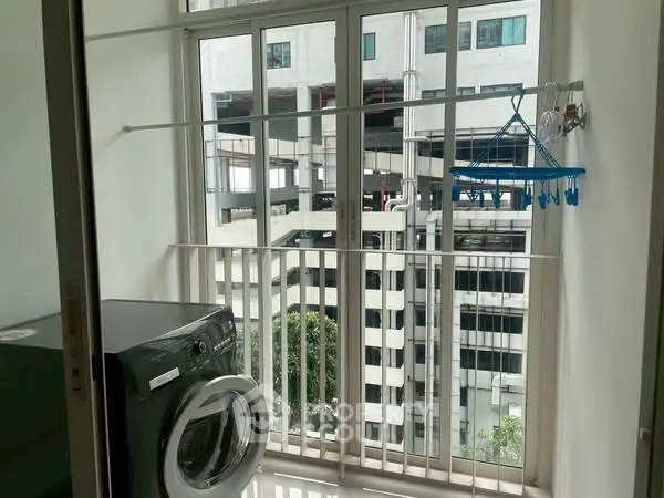 Modern laundry area with washing machine and city view from balcony.