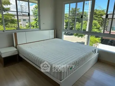 Bright bedroom with large windows and modern bed, offering a serene view of greenery.