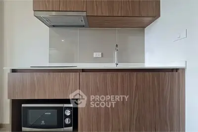 Modern kitchen with sleek wooden cabinets and built-in microwave, featuring a minimalist design.