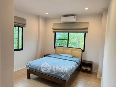 Spacious bedroom with large windows and modern decor, featuring a comfortable bed and air conditioning.