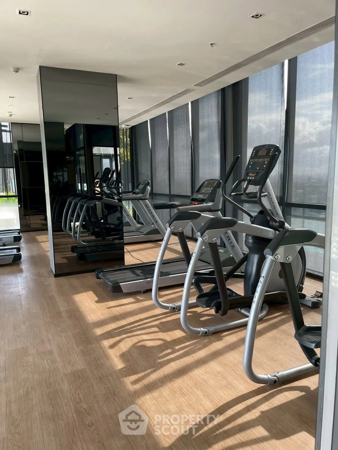 Modern gym with state-of-the-art equipment and floor-to-ceiling windows offering city views.