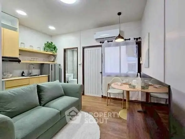 Cozy living room with modern kitchen and dining area, featuring stylish decor and natural light.