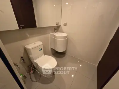 Modern bathroom with sleek fixtures and glossy tiles, featuring a compact design for efficient space use.