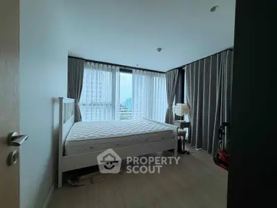 Spacious bedroom with large windows and city view, featuring a comfortable bed and elegant curtains.