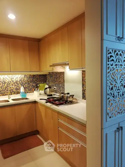 Modern kitchen with wooden cabinets and mosaic backsplash in cozy apartment
