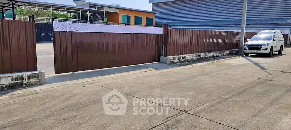 Industrial property with secure gated entrance and spacious parking area.