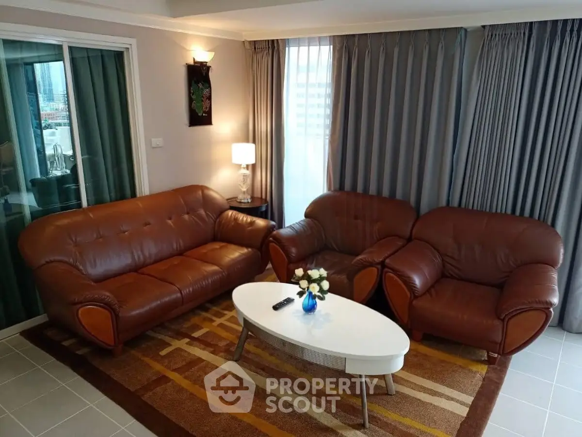 Spacious living room with elegant leather sofas and modern decor in a high-rise apartment.