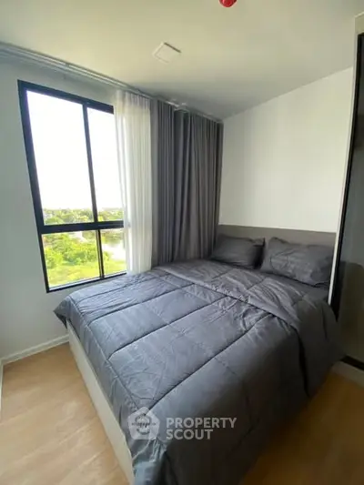 Cozy bedroom with large window and modern gray bedding in a bright apartment.