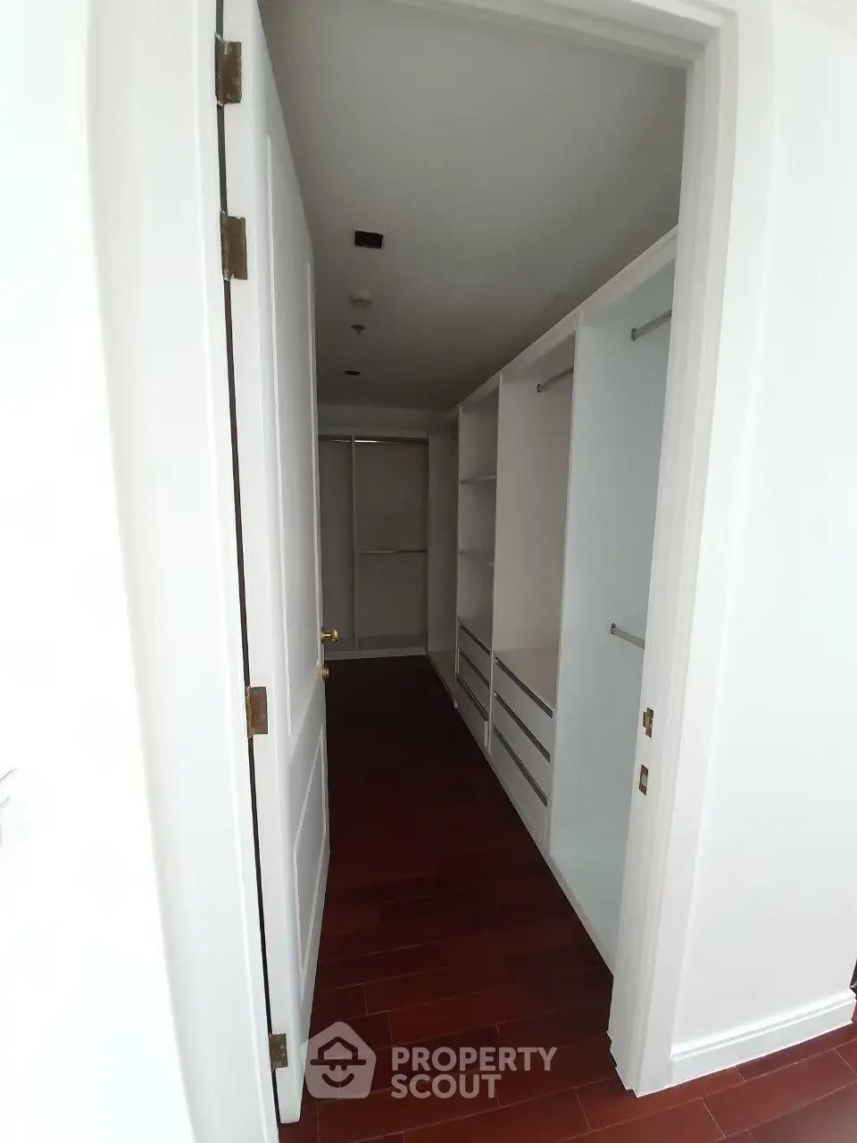 Spacious walk-in closet with elegant wooden flooring and ample storage space.