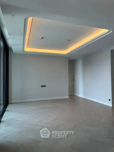 Spacious modern living room with elegant ceiling lighting and large windows.