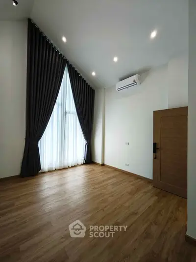 Spacious modern room with high ceiling and elegant floor-to-ceiling curtains