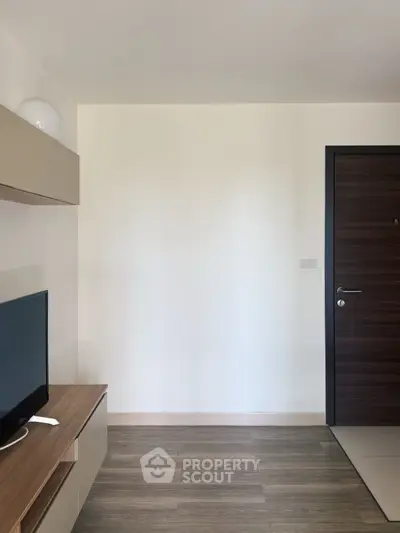 Modern apartment entrance with sleek wooden door and minimalist TV setup.