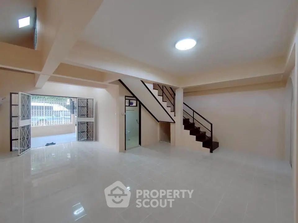Spacious open-plan living area with modern staircase and natural light