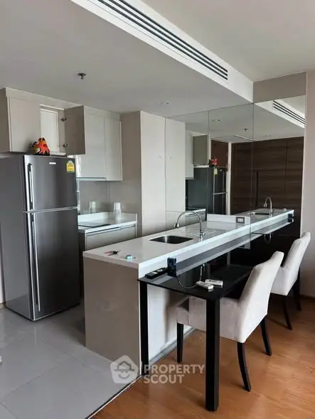 Modern kitchen with sleek design, featuring a breakfast bar and stainless steel appliances.