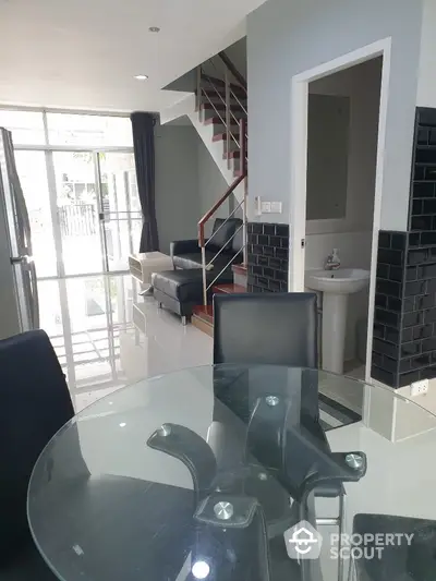 Modern townhouse interior with glass dining table and staircase