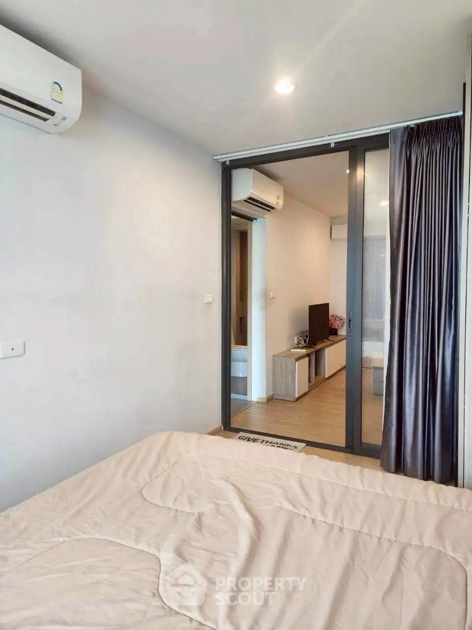 Modern bedroom with air conditioning and sliding glass doors in a stylish apartment.