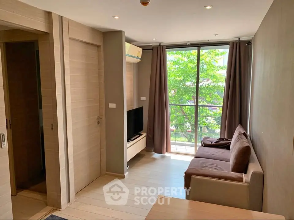 Modern living room with balcony view, featuring sleek furniture and natural light.