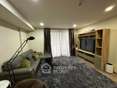 Spacious living room with modern furniture and large TV, perfect for relaxation and entertainment.
