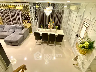 Luxurious living room with elegant dining area and plush sofa, featuring modern decor and chandelier lighting.