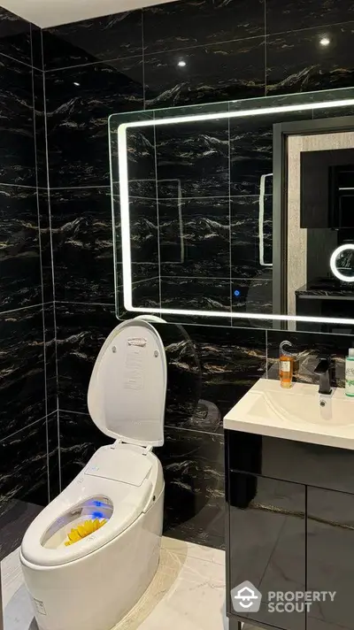 Luxurious modern bathroom with sleek black tiles and illuminated mirror