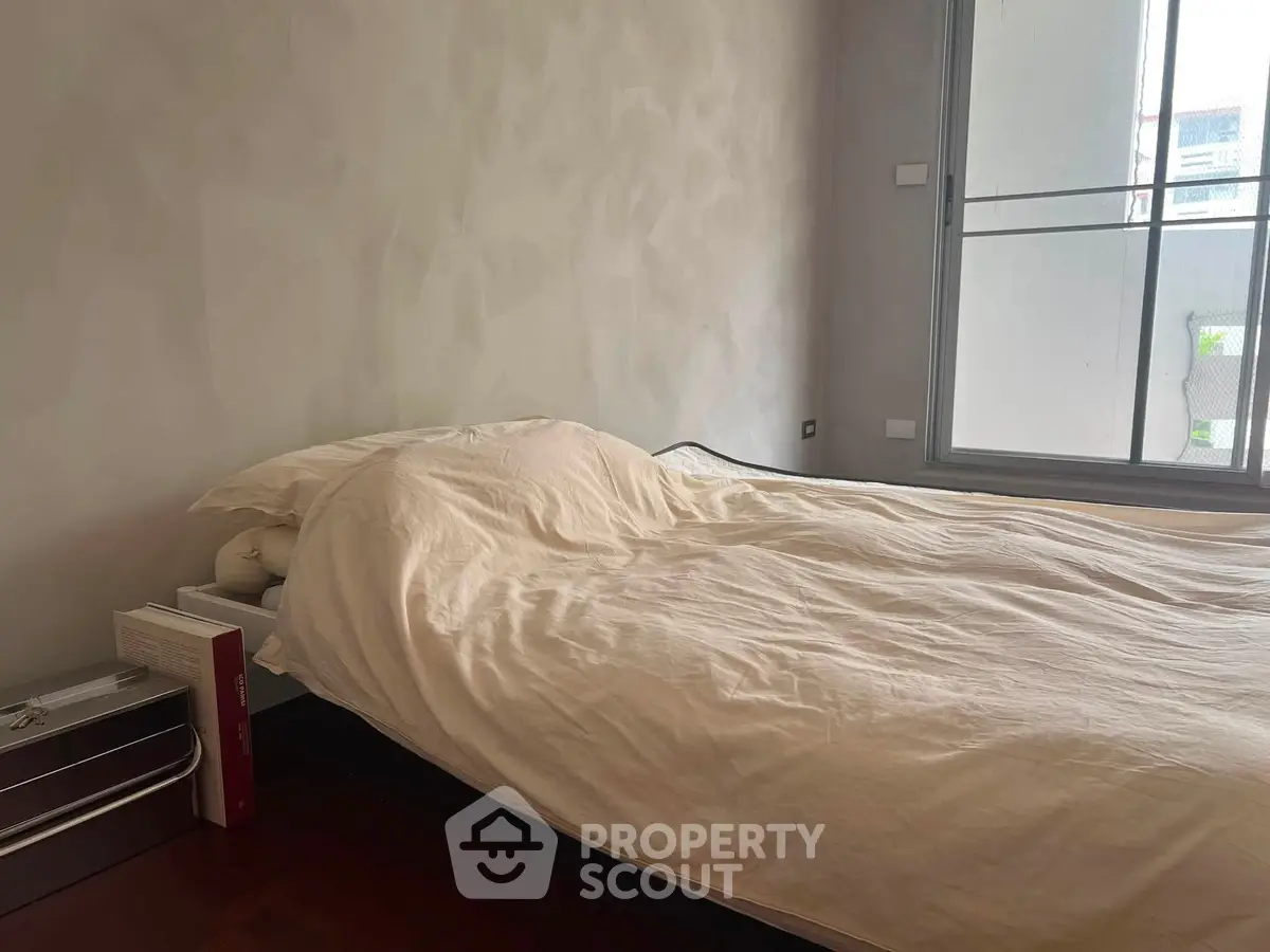 Cozy bedroom with large window and minimalist decor, perfect for relaxation and comfort.