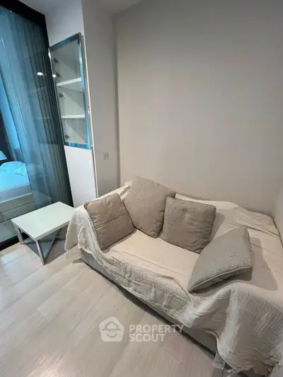 Cozy living room with modern sofa and glass partition leading to bedroom