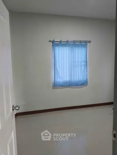 Minimalist bedroom with blue curtains and white door, perfect for cozy living.