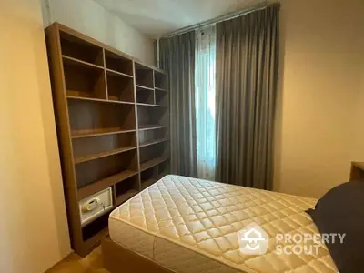 Cozy bedroom with ample natural light, featuring a large bed and spacious wooden bookshelf, ideal for comfortable living.