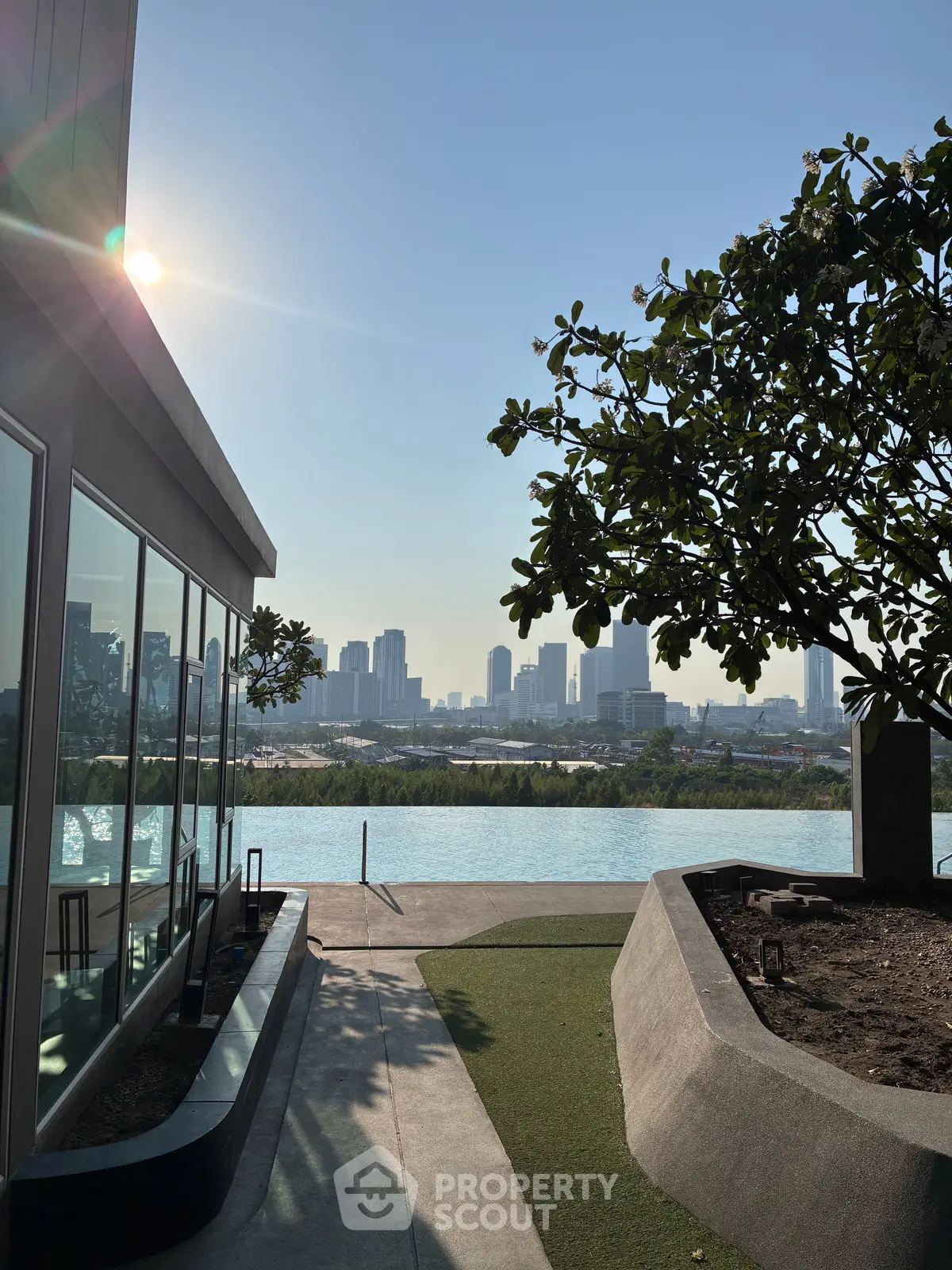 Stunning rooftop pool with city skyline view and lush greenery, perfect for relaxation and urban living.