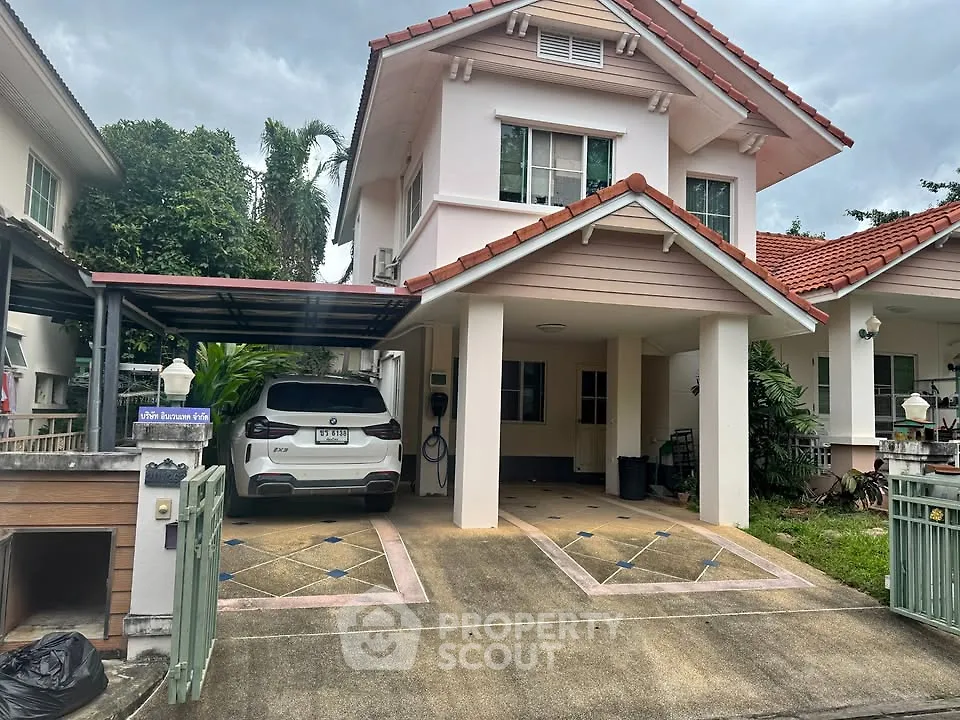 Charming two-story house with carport and lush greenery in a serene neighborhood.
