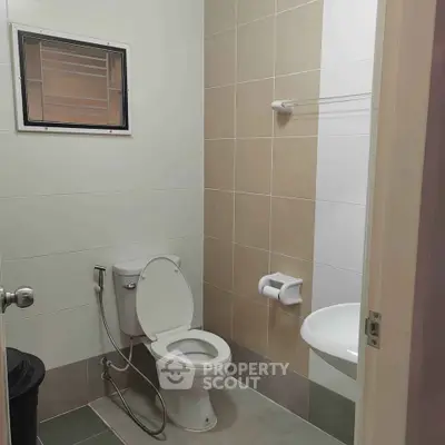 Modern bathroom with sleek design and neutral tiles, featuring a toilet and sink.