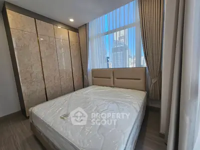 Modern bedroom with large windows and city view, featuring elegant curtains and a comfortable bed.